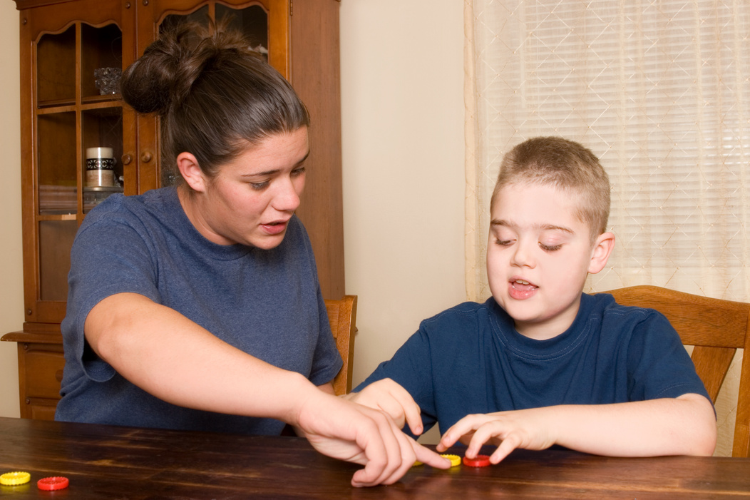 Young woman giving small boy therapy for behavior analysis